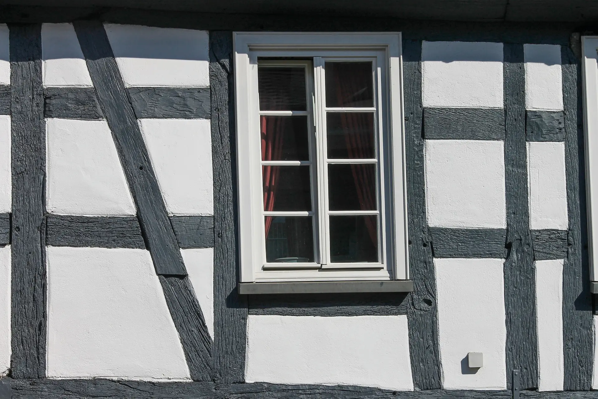 Fachwerkfassade eines Bestandsgebäudes mit dunklen Holzbalken und weißen Gefachen